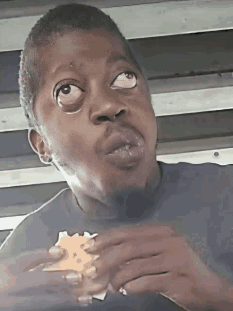 a young boy eating a sandwich with his eyes closed