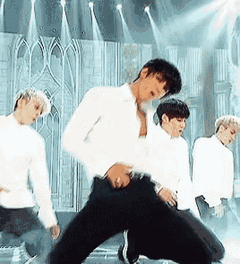 a man in a white shirt is dancing on stage with other men .