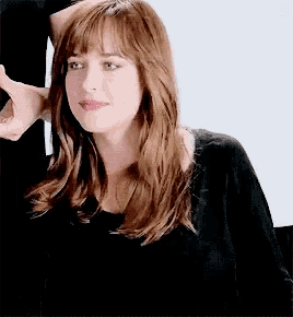 a woman with long brown hair and bangs is wearing a black shirt