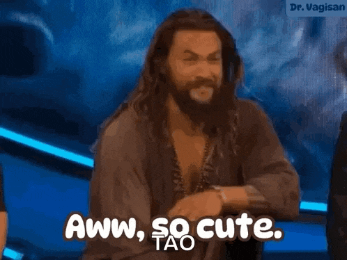 a man with a beard is standing in front of a blue background and says aww , so cute .