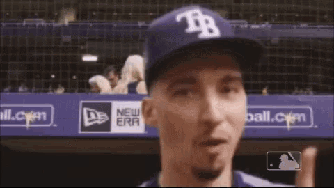 a man wearing a hat with the letter tr on it points up