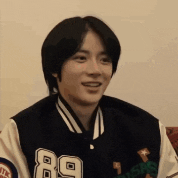 a young man wearing a varsity jacket is smiling .