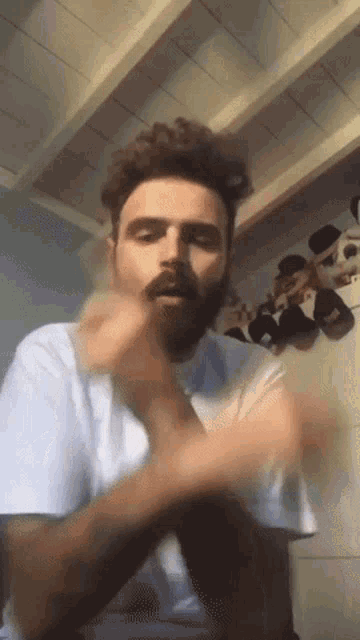 a man with a beard wearing a white shirt is making a funny face