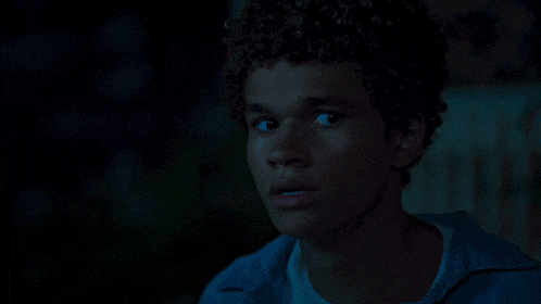 a young man with curly hair looks at the camera