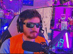 a man wearing headphones and sunglasses is sitting in front of a microphone in a room .