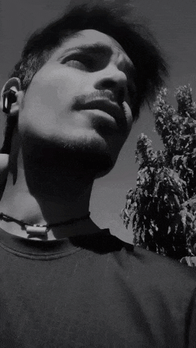 a black and white photo of a man 's face with a tree in the background