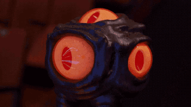 a close up of a sculpture with orange eyes