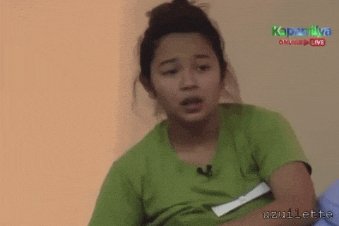 a woman in a green shirt is sitting in front of a sign that says kapamilya on it