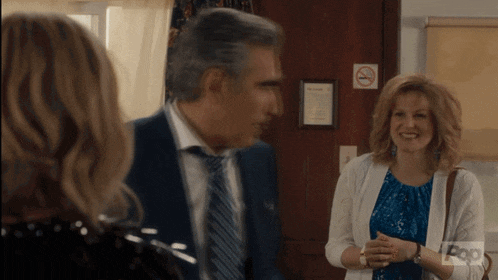 a man in a suit and tie is talking to two women