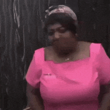 a woman in a pink shirt is holding her chest and crying .
