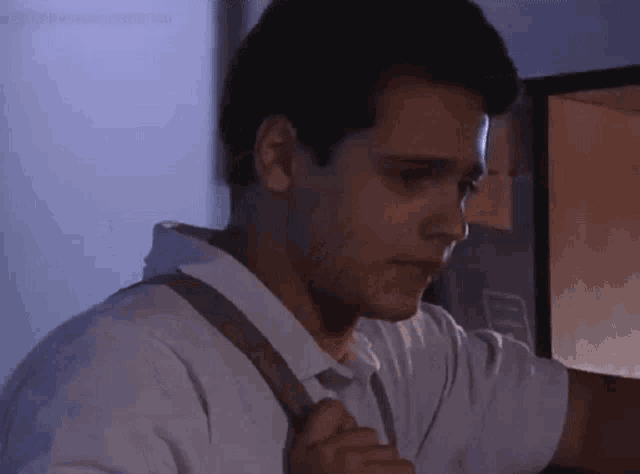 a man in a white shirt is standing in front of a door .