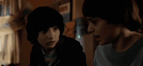 a couple of young boys are standing next to each other in a dark room .
