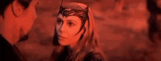 a woman with a crown on her head is looking at a man .