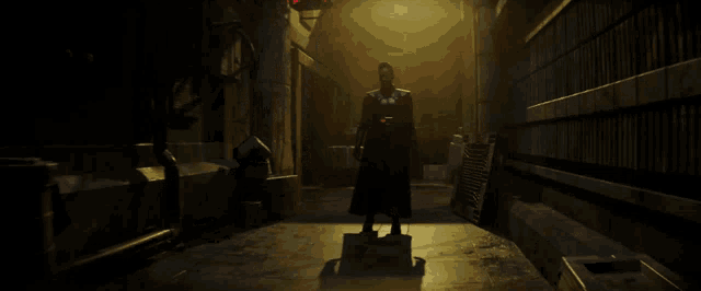 a man in a black cape stands in a dark room