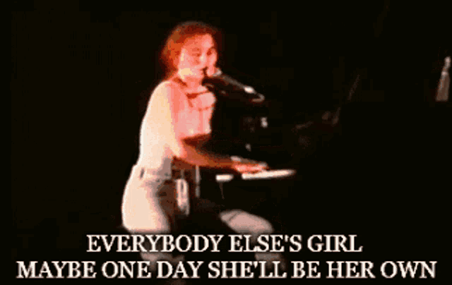a woman singing into a microphone while playing the piano