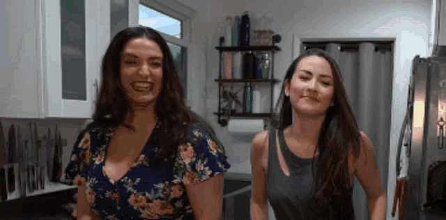 two women are standing next to each other in a kitchen