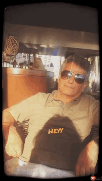 a man wearing sunglasses and a shirt with the word hey on it