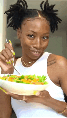 a woman is holding a bowl of food with a fork in her hand .