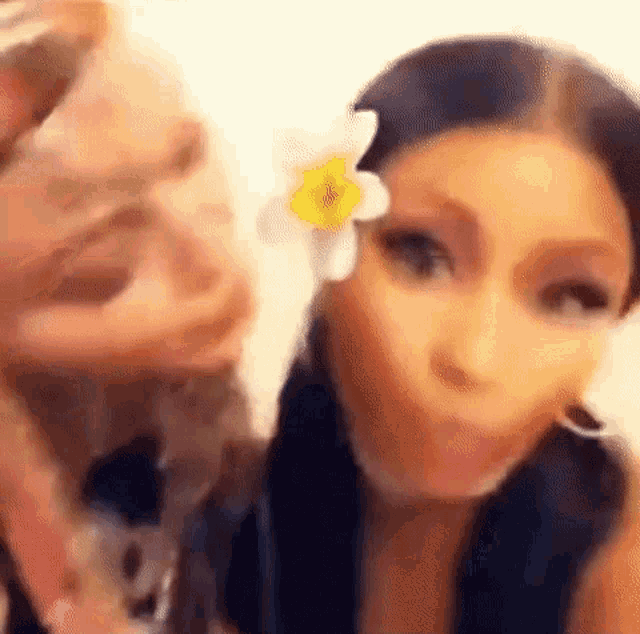 a woman with a flower in her hair is making a funny face .