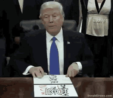 donald trump is sitting at a table with a sign that says " please do not vote "