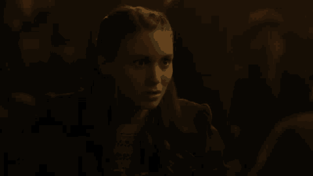 a young woman is sitting in a dark room looking at something .