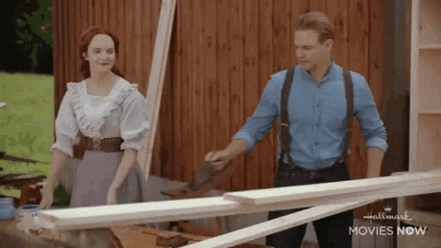 a man and a woman are standing next to each other in front of a wooden fence .