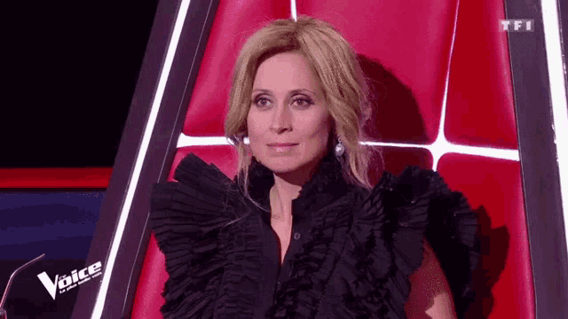 a woman is sitting in a red chair with the word voice on it