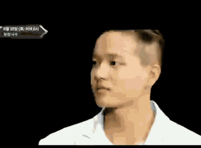 a man with a shaved head and a white shirt is looking at something .