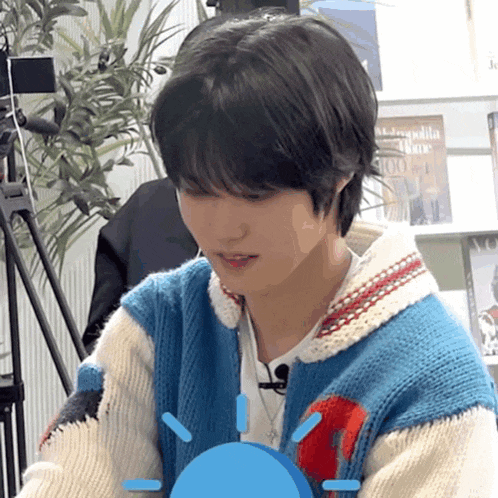 a young man wearing a blue and white sweater is looking at something
