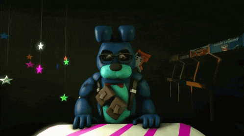 a blue stuffed animal is sitting on a table with a sign that says arcade legends
