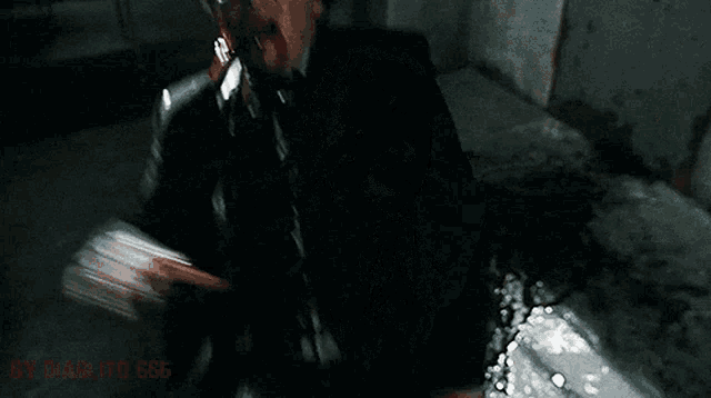 a man in a suit and tie with blood coming out of his mouth is sitting on the ground