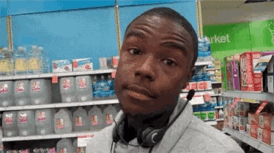 a man wearing headphones is standing in a grocery store with a sign that says market in the background .