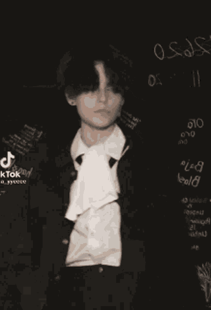 a man in a suit and tie is dancing in front of a blackboard with the number 8 on it .