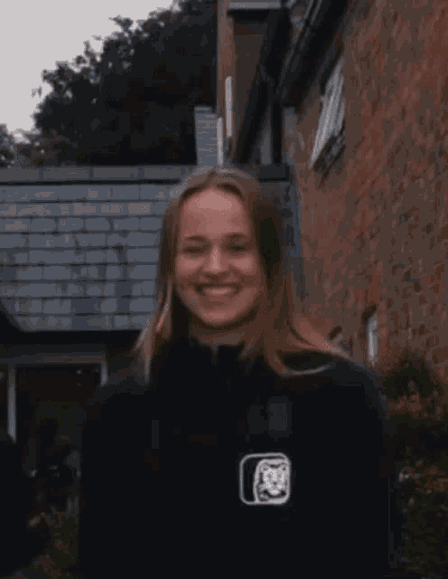 a young woman is smiling in front of a brick building