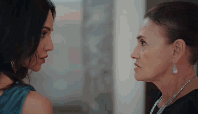 two women are standing next to each other and looking at each other .