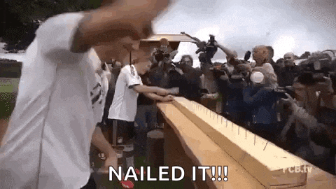 a man is standing on a wooden board with nails in it and a crowd of people watching .