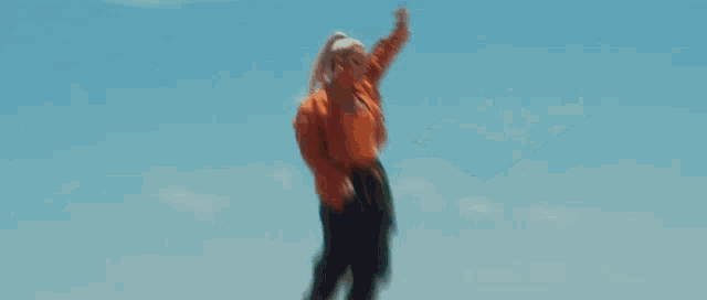 a woman wearing an orange jacket and hoop earrings is looking down at the camera .