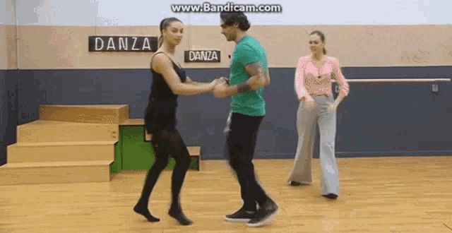 a man and woman are dancing in a dance studio with a sign that says danza on it