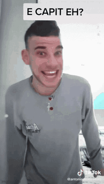 a man wearing a grey shirt with the word e capit eh written on it