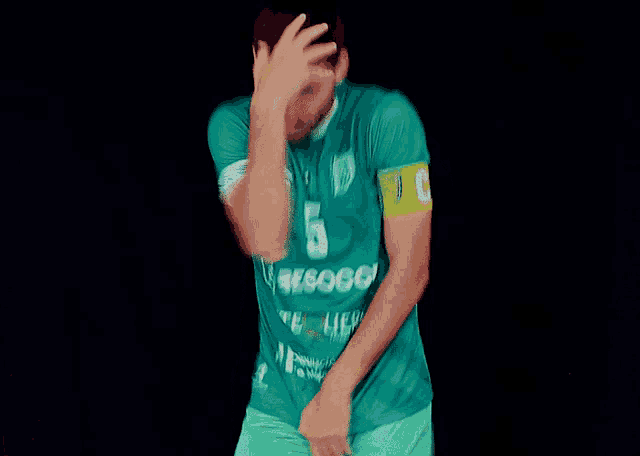 a soccer player wearing a green jersey with the number 5 on it
