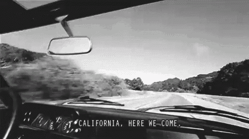 a black and white photo of a car driving down a road with california here we come written on the dashboard