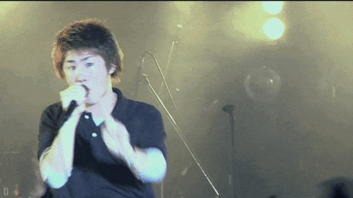 a man singing into a microphone with the letter d on the bottom left