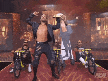 a group of men are riding bikes on a stage that says aew on it