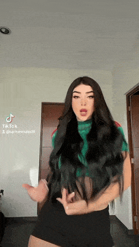 a woman with long black hair is dancing in front of a door with a tiktok watermark