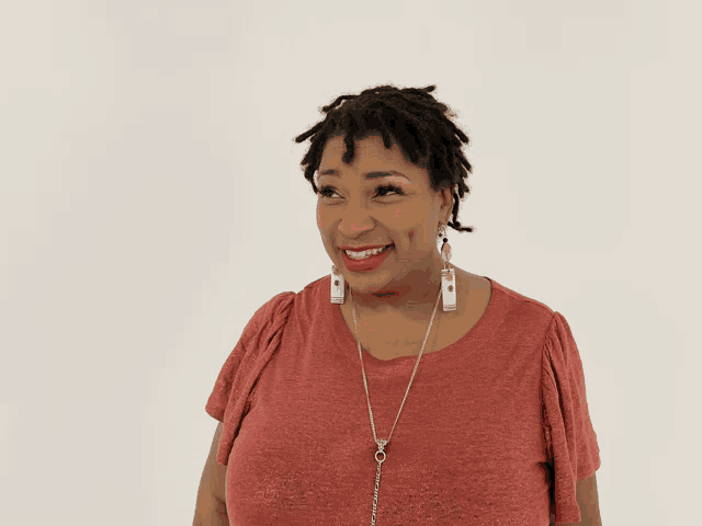 a woman wearing earrings and a red shirt smiles