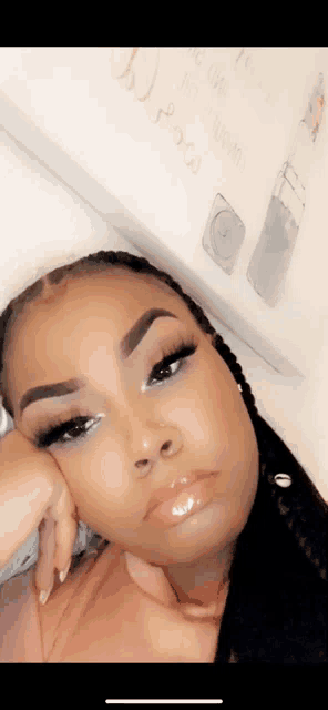 a woman laying on a bed with her hand on her chin