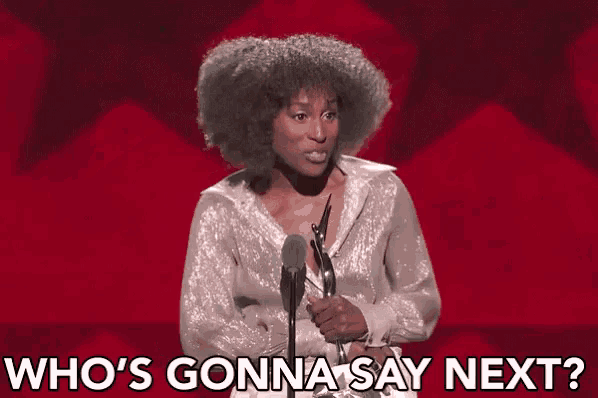 a woman is holding a trophy in front of a microphone and says who 's gonna say next ?