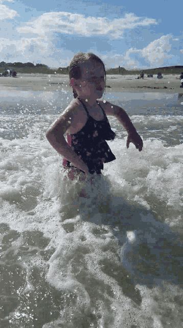 a little girl in a bathing suit is running in the water