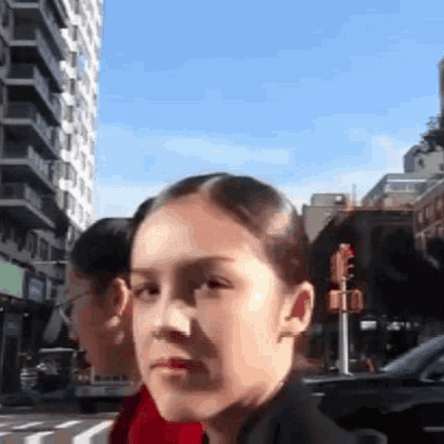 a woman is standing on a city street looking at the camera