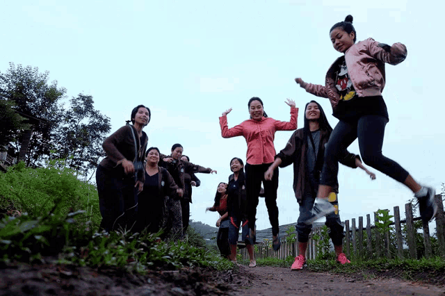 a girl in a pink jacket with mickey mouse on it is jumping in the air